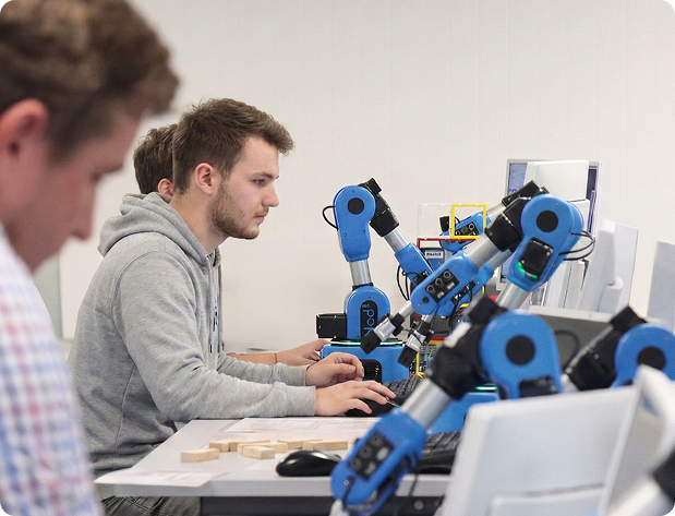 Studenti che lavorano con bracci robotici educativi programmabili in un ambiente di formazione in robotica.